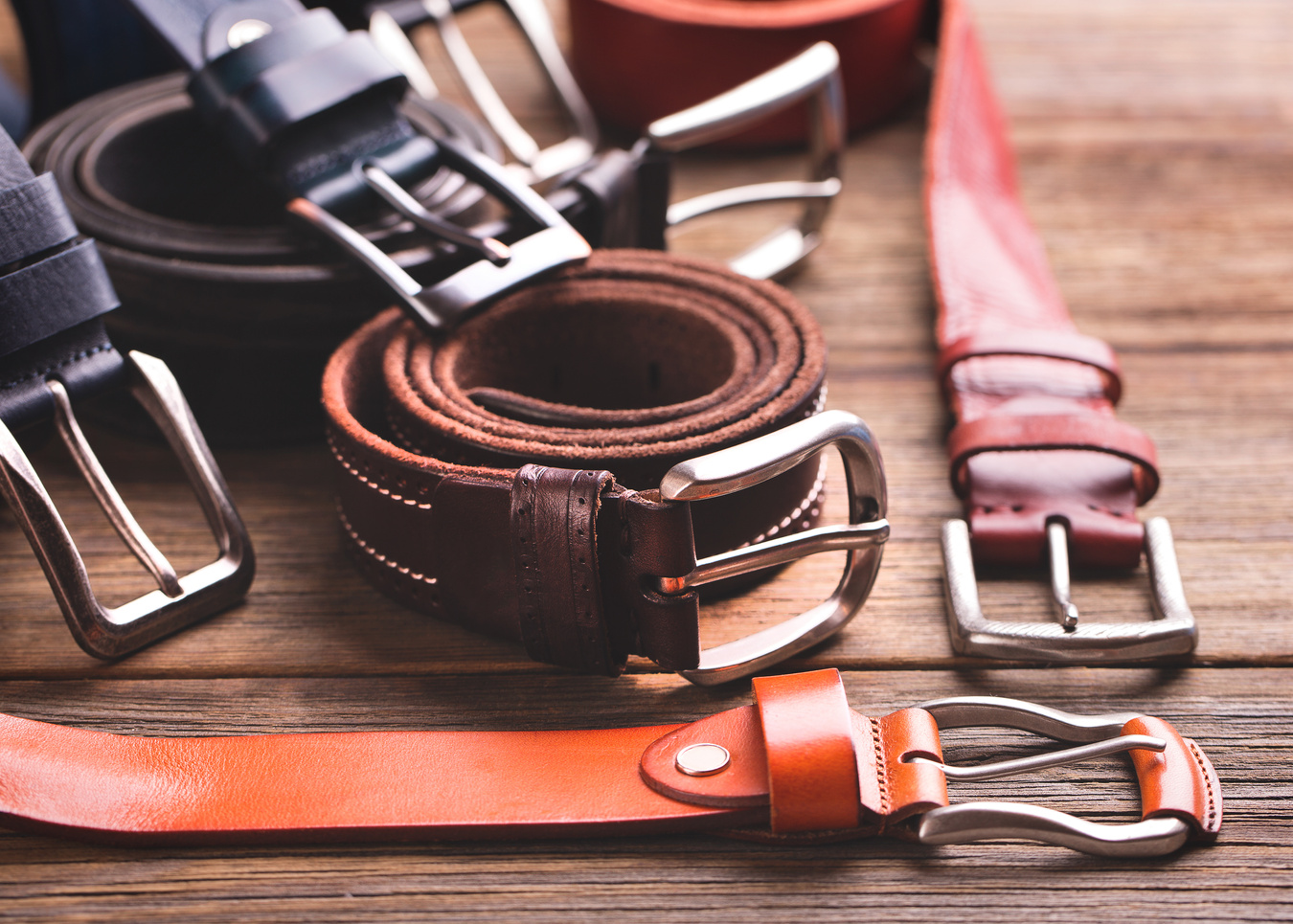 Collection of leather belts on a wooden table